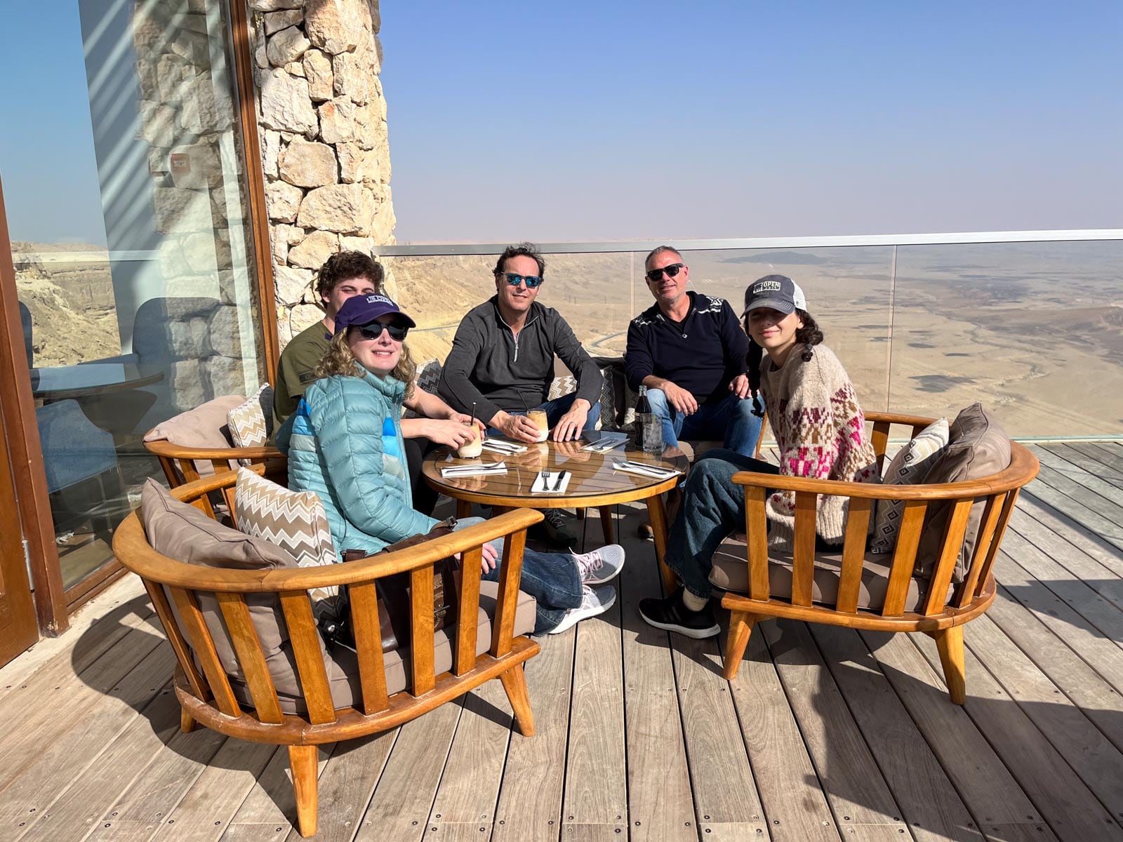 A group of people sitting on a deck overlooking the desert.