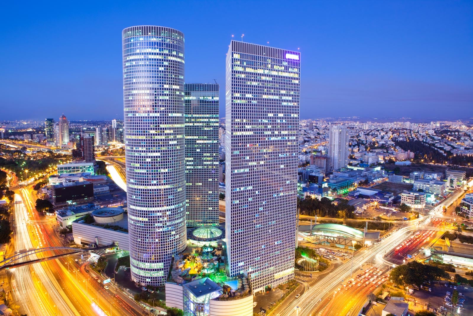 Two tall buildings in a city at night, capturing the vibrant essence of a Tel-aviv, Israel.