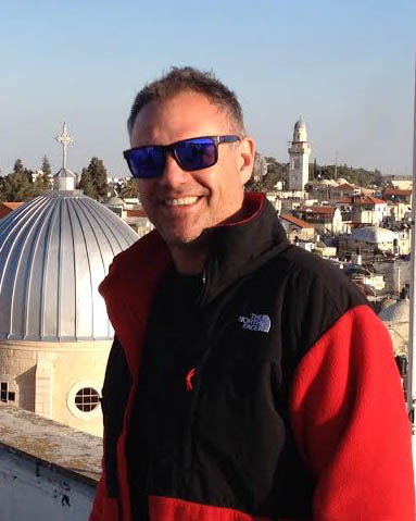 A man wearing sunglasses in front of a building in jerusalem.