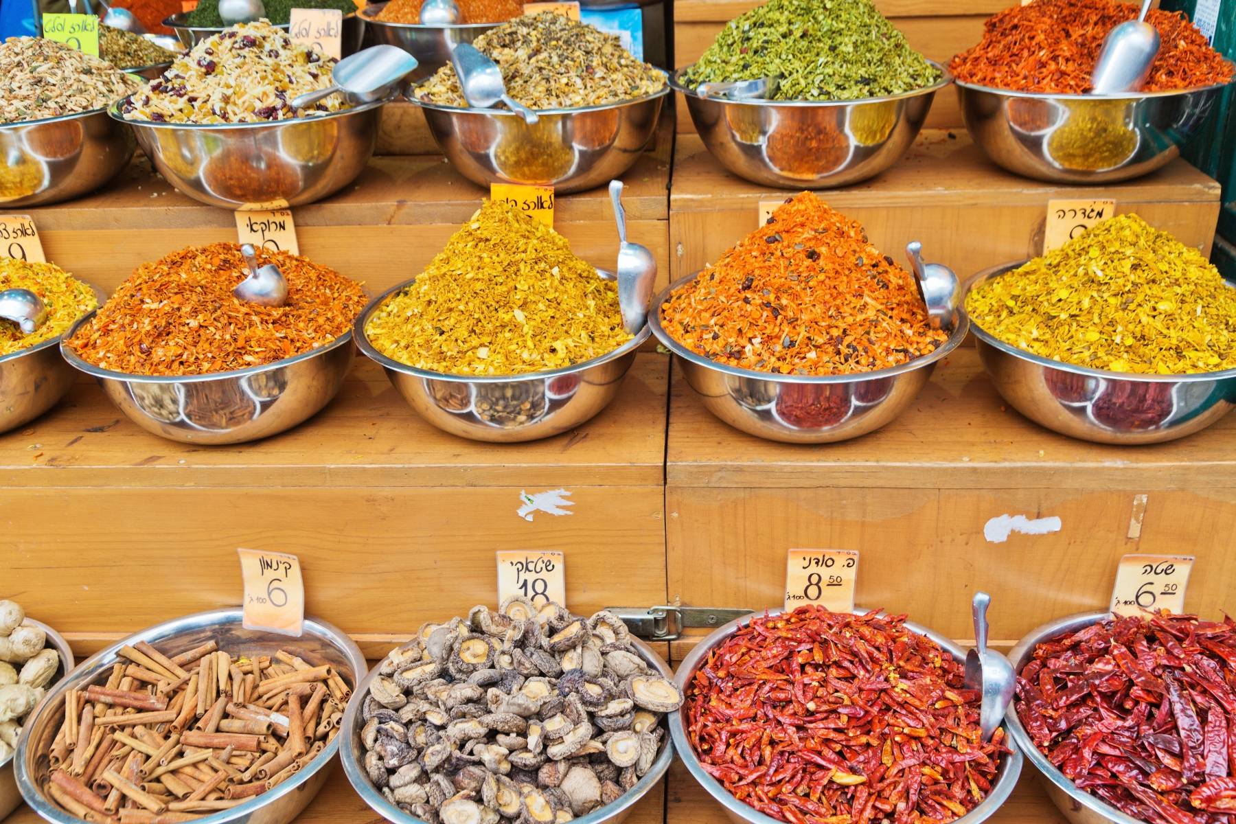 Assorted spices and herbs displayed in metal bowls at a market stall.